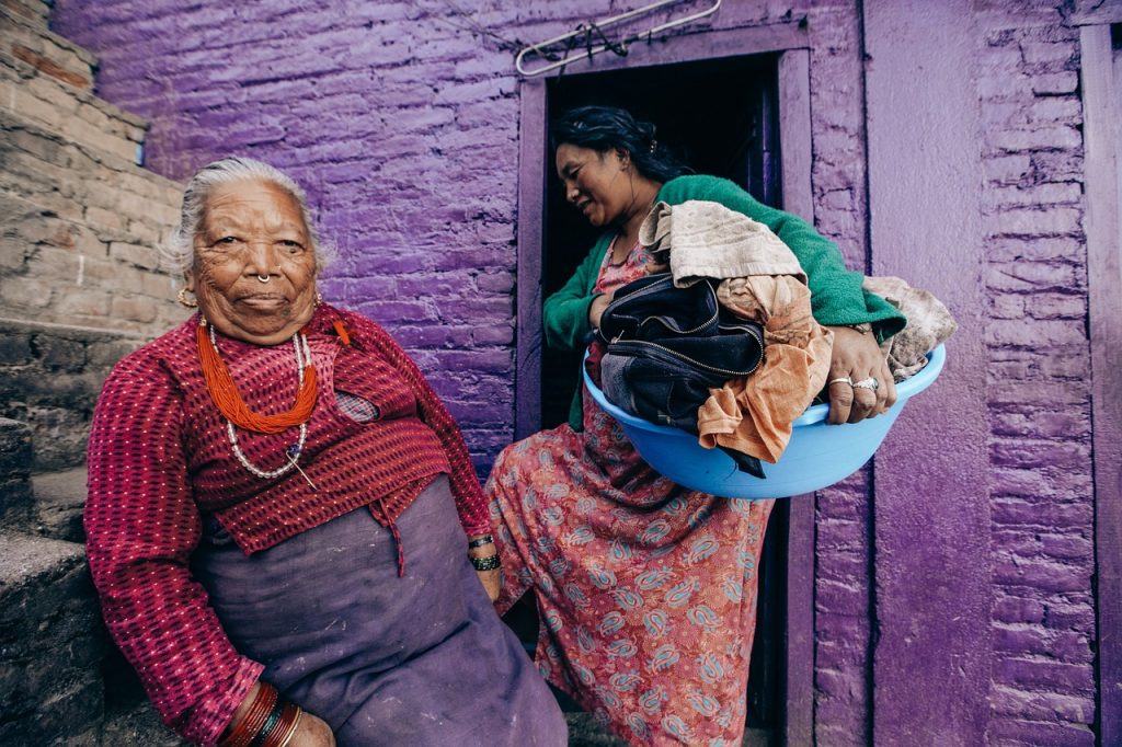Een zorgmedewerker helpt een oudere bewoner in een verpleeghuis