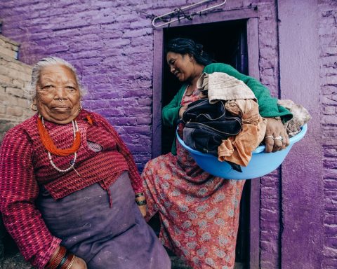 Een zorgmedewerker helpt een oudere bewoner in een verpleeghuis