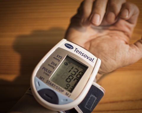 Persoon die thuis bloeddruk meet met een bovenaarmsmeter
