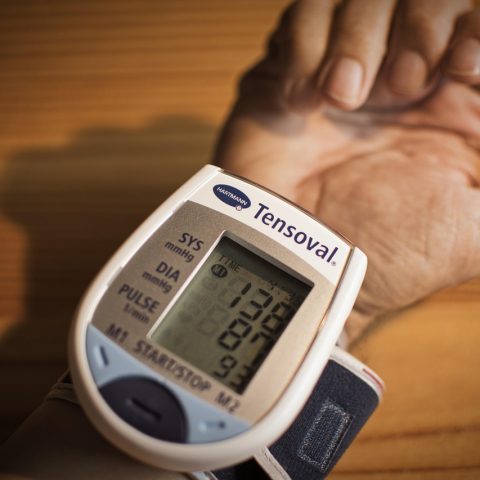 Persoon die thuis bloeddruk meet met een bovenaarmsmeter