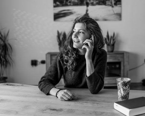 Een oudere man en vrouw in gesprek met een verpleegkundige aan de keukentafel thuis