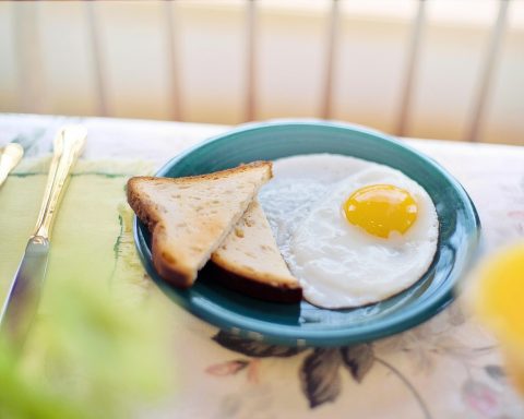 Een gedekte ontbijttafel met yoghurt, fruit, noten en volkorenbrood