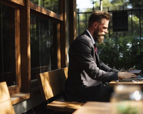 Persoon die werkt aan een bureau naast een raam met herfstlicht buiten