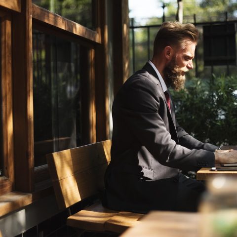 Persoon die werkt aan een bureau naast een raam met herfstlicht buiten