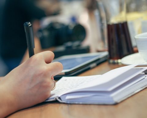 Persoon schrijft dagelijkse gewoonten op in een notitieboekje aan een keukentafel