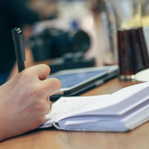 Persoon schrijft dagelijkse gewoonten op in een notitieboekje aan een keukentafel
