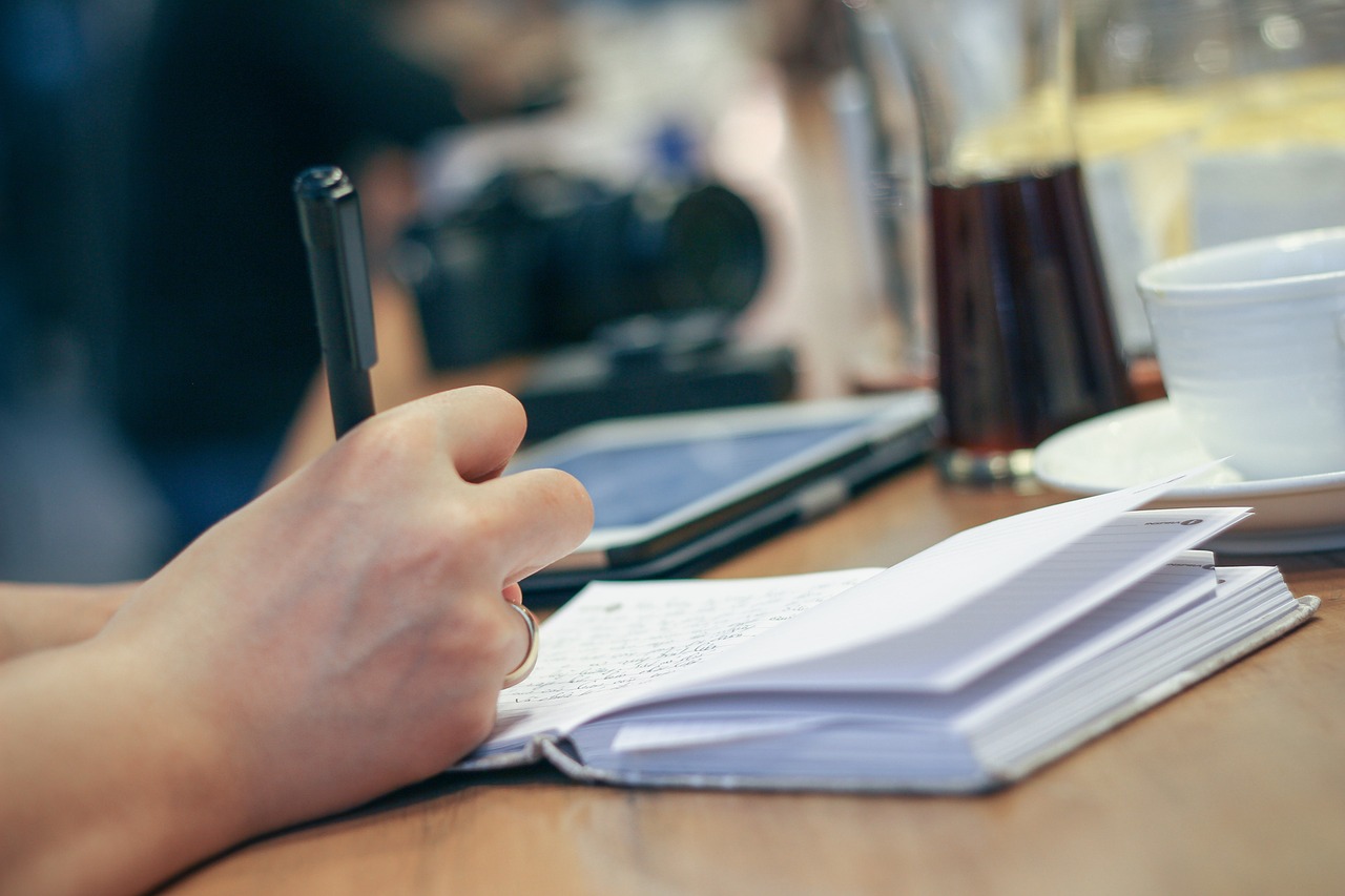 Persoon schrijft dagelijkse gewoonten op in een notitieboekje aan een keukentafel