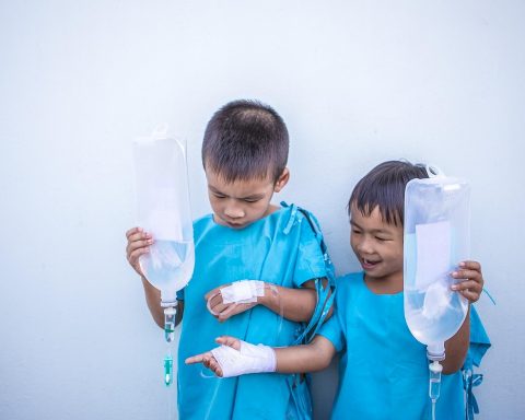 Persoon ligt ziek in bed met een thermometer en een glas water op het nachtkastje