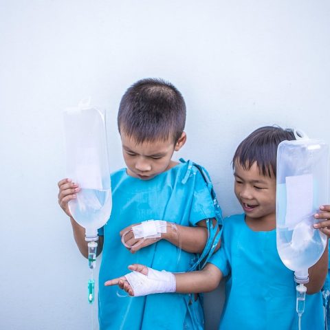 Persoon ligt ziek in bed met een thermometer en een glas water op het nachtkastje
