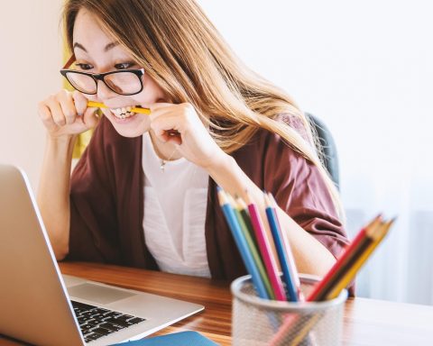 Persoon die zorgverzekeringen vergelijkt op laptop met papieren documenten naast zich