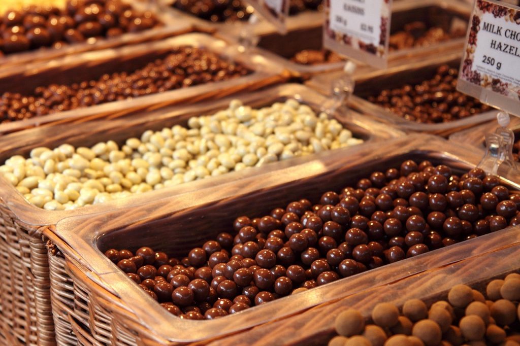 Een houten plank met verschillende noten, zaden en stukjes pure chocolade als koperrijke voedingsmiddelen