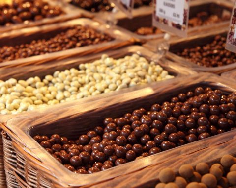 Een houten plank met verschillende noten, zaden en stukjes pure chocolade als koperrijke voedingsmiddelen