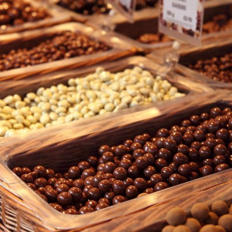 Een houten plank met verschillende noten, zaden en stukjes pure chocolade als koperrijke voedingsmiddelen