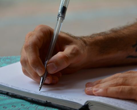 Persoon schrijft in een dagboek aan een bureau om stemming en gedachten bij te houden