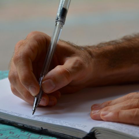 Persoon schrijft in een dagboek aan een bureau om stemming en gedachten bij te houden