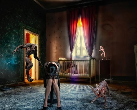 Vrouw met migraine ligt in een donkere kamer met haar handen tegen haar hoofd