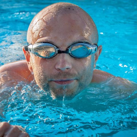 Zwemmer met zwembril in een buitenbad op een zonnige dag