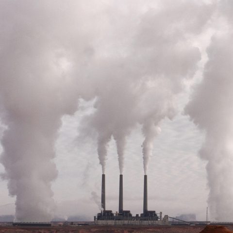 Schoorsteen van een industriegebied met rook tegen een bewolkte lucht