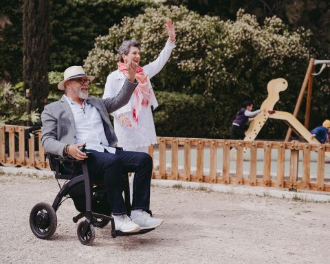 Oudere vrouw loopt met een rollator op een klinkerpad buiten
