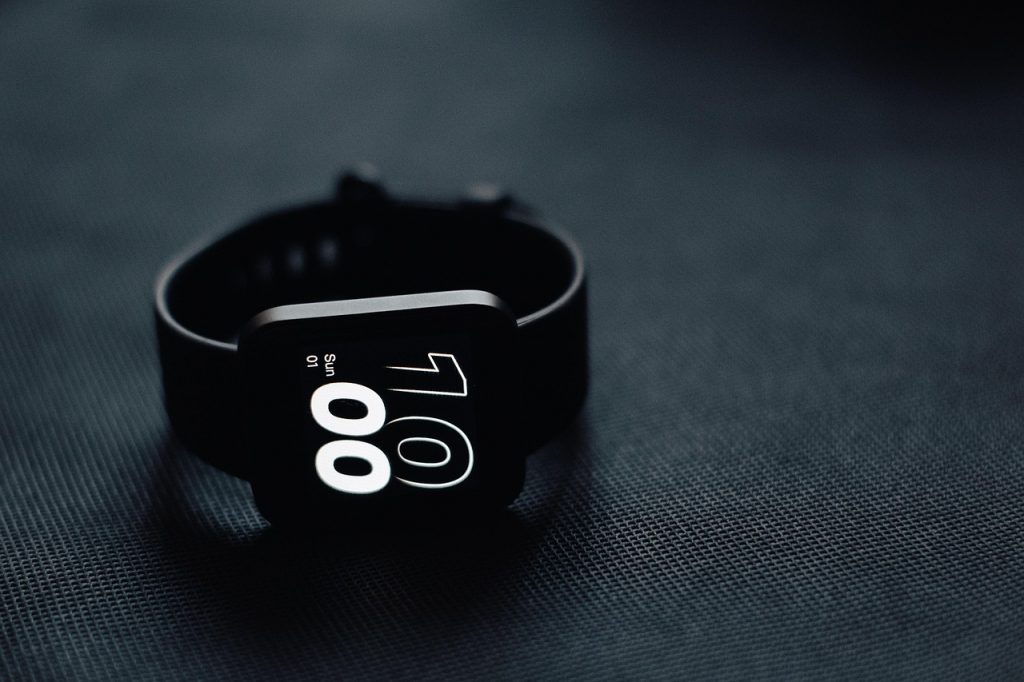 Een smartwatch op een nachtkastje naast een slapend persoon die slaapgegevens bijhoudt