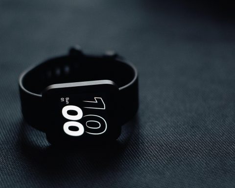 Een smartwatch op een nachtkastje naast een slapend persoon die slaapgegevens bijhoudt