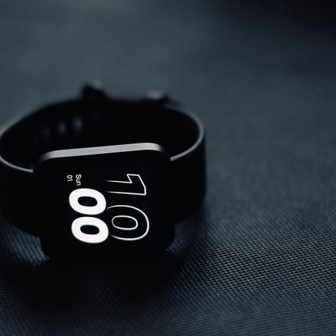Een smartwatch op een nachtkastje naast een slapend persoon die slaapgegevens bijhoudt