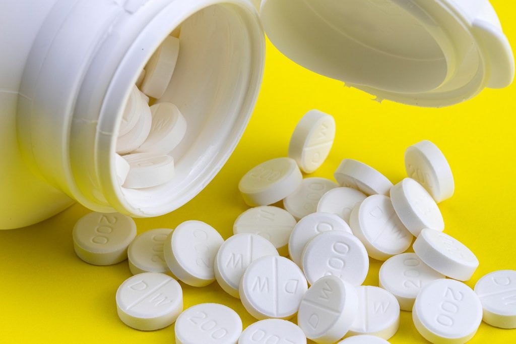 Verschillende supplementenpotjes met vitamine D, zink en probiotica op een plank in een drogisterij