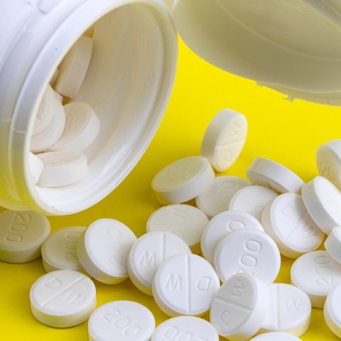 Verschillende supplementenpotjes met vitamine D, zink en probiotica op een plank in een drogisterij