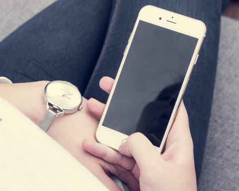 Persoon die een symptoomchecker op de smartphone gebruikt terwijl hij op de bank zit