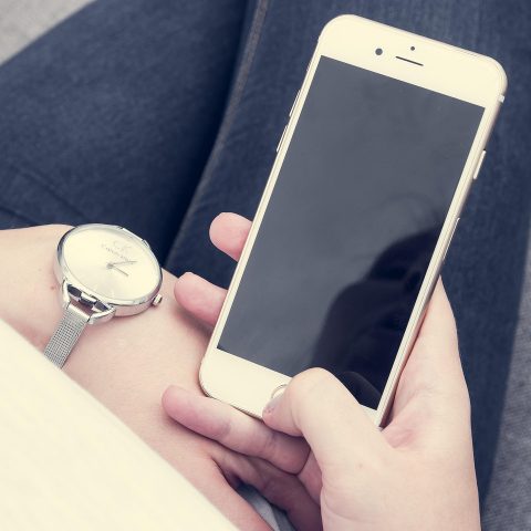Persoon die een symptoomchecker op de smartphone gebruikt terwijl hij op de bank zit