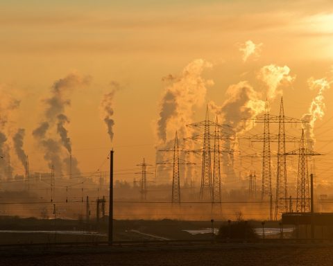 Rookpluimen boven een staalfabriek met omliggende woonwijk op de achtergrond