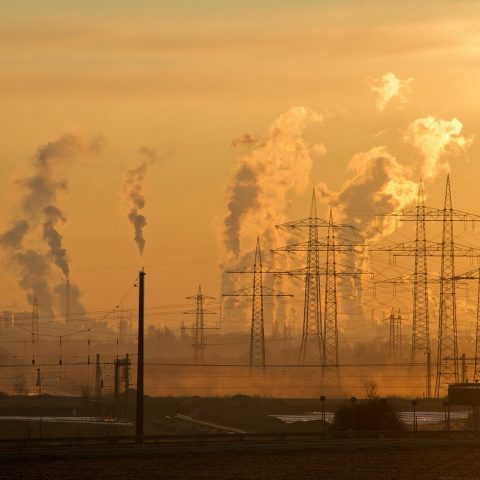 Rookpluimen boven een staalfabriek met omliggende woonwijk op de achtergrond