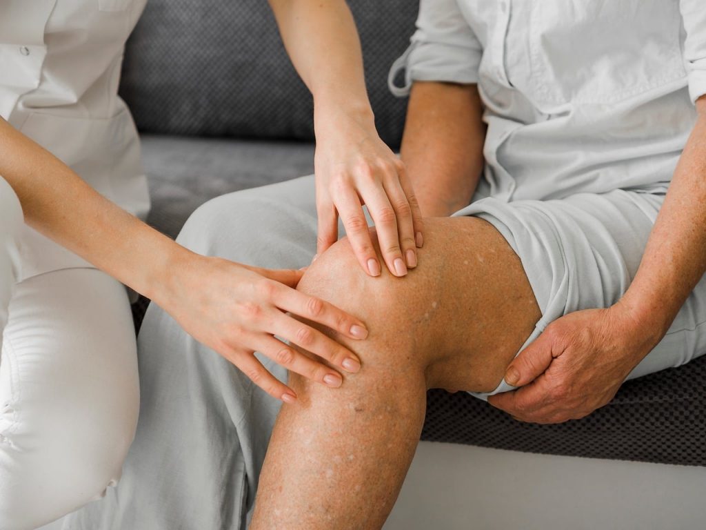 Persoon voert een revalidatieoefening uit voor de knie op een yogamat