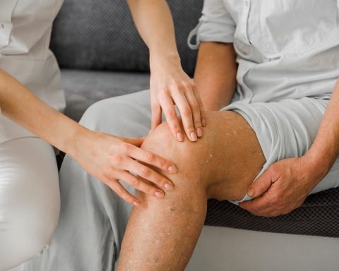 Persoon voert een revalidatieoefening uit voor de knie op een yogamat