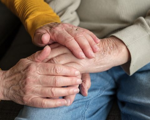 Een verpleegkundige helpt een oudere vrouw thuis met haar verzorging