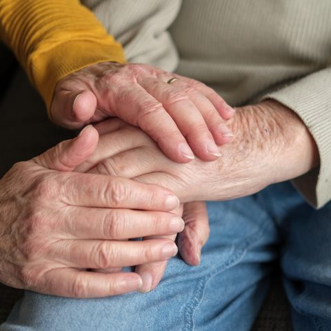 Een verpleegkundige helpt een oudere vrouw thuis met haar verzorging