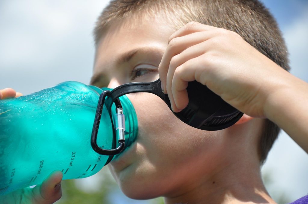 Persoon drinkt een glas water op een zonnige zomerdag buiten