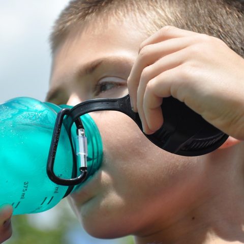 Persoon drinkt een glas water op een zonnige zomerdag buiten
