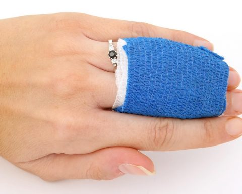 Persoon wisselt thuis een verband op de arm na een kleine operatie