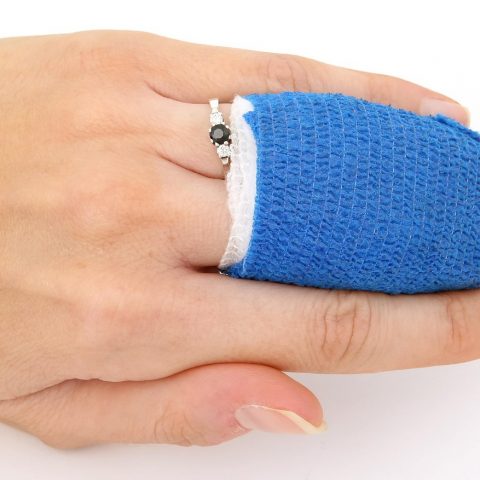 Persoon wisselt thuis een verband op de arm na een kleine operatie